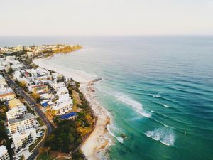 A stunning aerial view of Caloundra Beach, Queensland at sunset with waves and coastline.